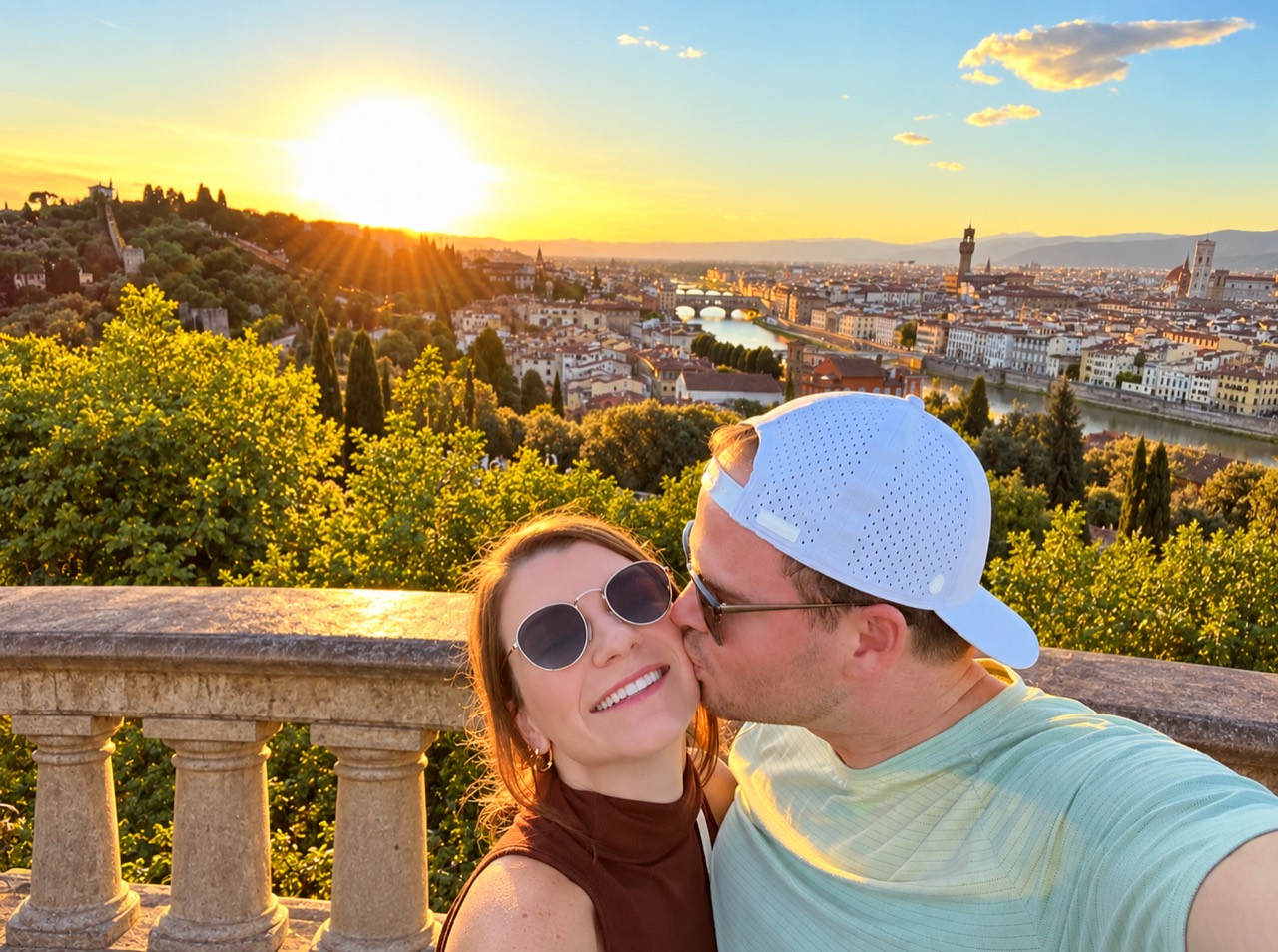 Jay kissing Katie's cheek above an Italian city at sunset